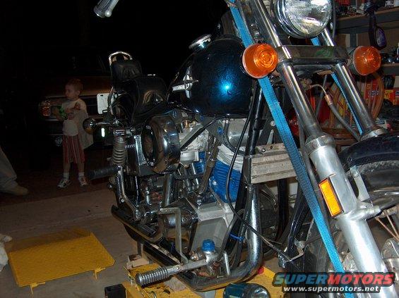 Close-up of a motorcycle engine and frame, with a child in the background