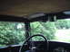 1929 Ford Model A - Interior view of a 1929 Ford Model A, showing the steering wheel and a side window with trees visible greenery outside greenery outside gre…