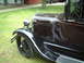 1929 Ford Model A - A close-up view of the front fender and grille of a dark-colored vintage automobile parked on grass.