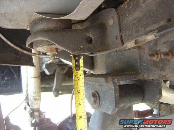 Close-up of a yellow tape measure against vehicle frame and suspension components