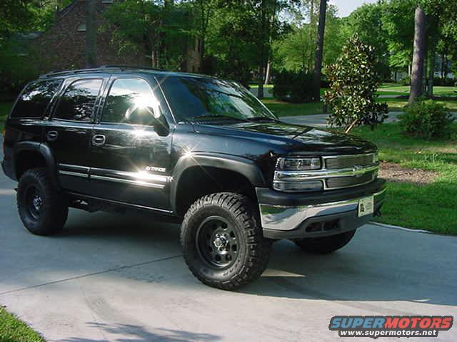 Black Chevrolet Tahoe parked on a driveway, lifted with off-road tires