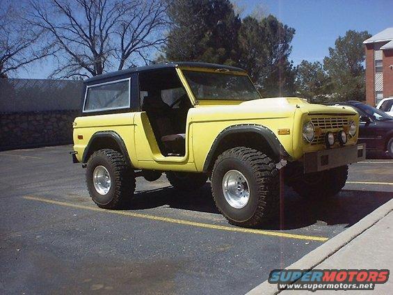 Yellow 1972 Ford Bronco with black hardtop and aftermarket bumper parked in a lot