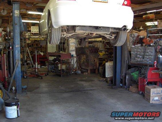 Rear view of white 2005 Scion tC on a lift in a garage. License plate visible