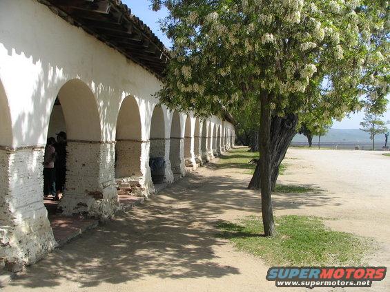 Mission walkway with white arched colonnade and flowering trees