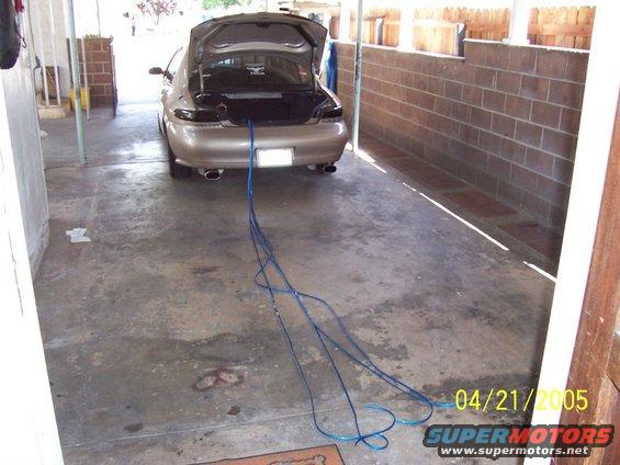 Car with trunk open, blue cables running out of it onto the ground