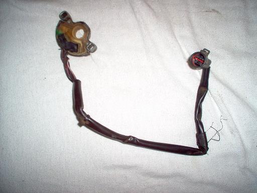 Electrical connector with red and black wires, attached to a wiring harness