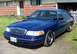 1998 Ford Crown Victoria - This 1998 Ford Crown Victoria features a distinctive chrome grille and is seen parked in front of a residential building.