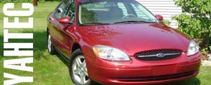 Red sedan with a Ford emblem on the grille, parked on grass
