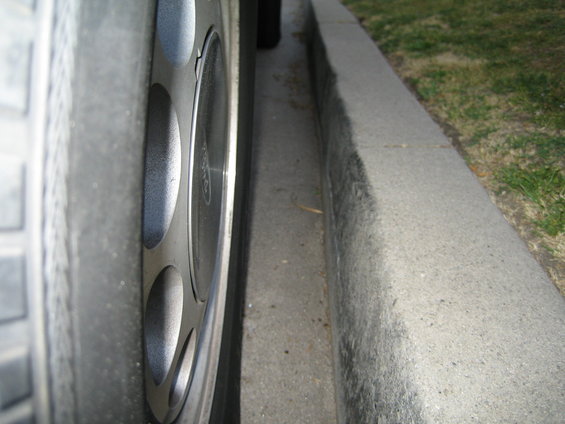 Close-up of a car wheel next to a concrete curb