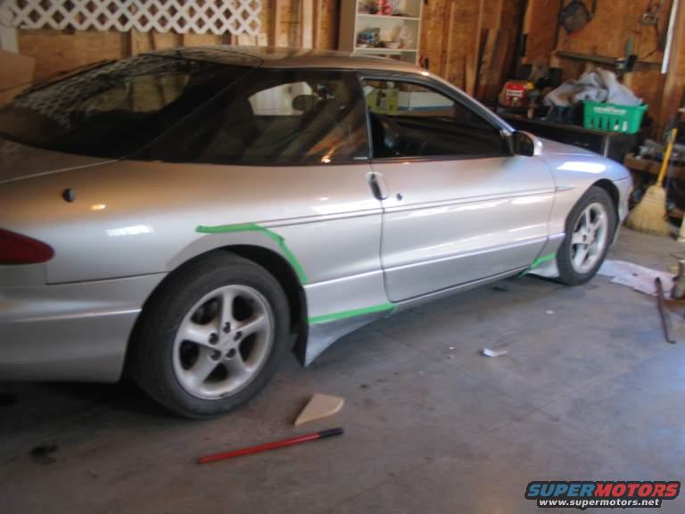 Silver 1993 Ford Probe coupe with green tape marking side skirt modifications, parked in a garage