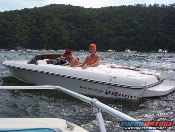 White speed boat with red trim, U-19 graphics, and two people aboard, on water