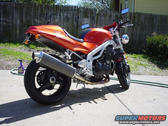 Orange 1997 Triumph Speed Four motorcycle parked on concrete, rear 3/4 view