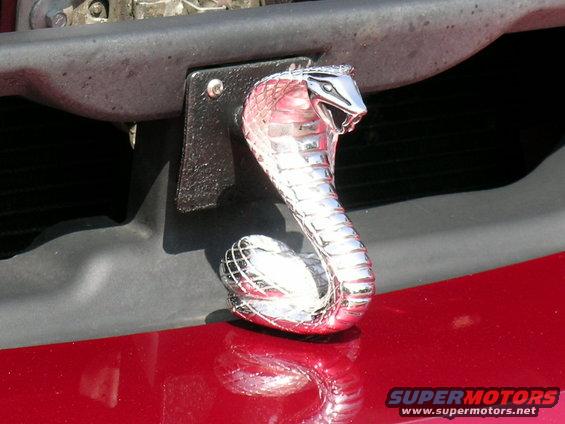 Chrome cobra hood ornament on a red car's front end