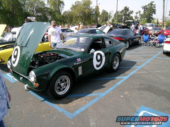 Green race car with number 9 on door and hood open, showing engine