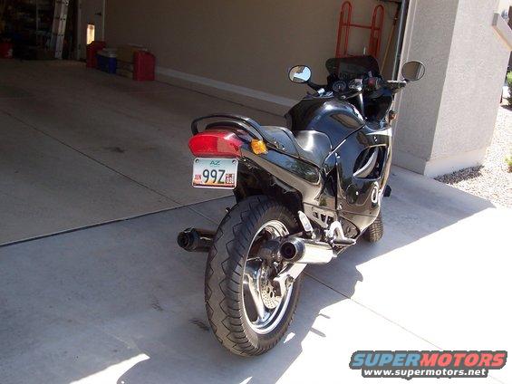 Black motorcycle parked in a garage, rear view showing license plate