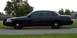 2001 Ford Crown Victoria - A dark 2001 Ford Crown Victoria sedan is parked on the side of the road.