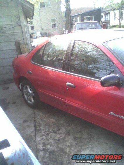 Red sedan side view, with handwritten numbers on door