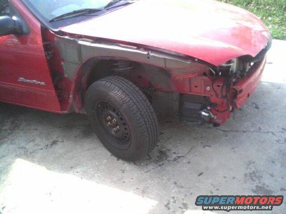 red car missing front bumper and fender, tire visible