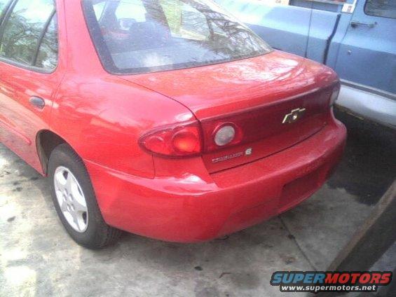 Rear quarter view of a red 2005 Chevrolet Cavalier sedan parked next to a blue pickup truck