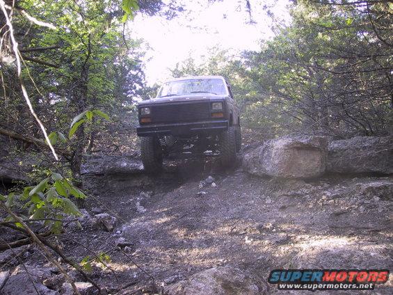 Front view of a dark off-road SUV navigating a rocky trail