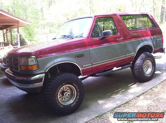 Red and gray Ford Bronco with off-road tires parked on a concrete driveway