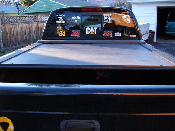 black pickup truck tailgate with a retractable cover and stickers on the rear window