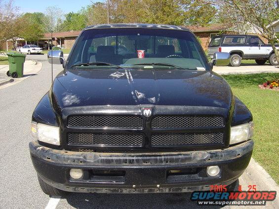 Front view of a black Dodge pickup truck. A white sedan and a two-tone SUV are in the background