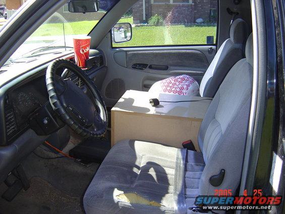 1997 Dodge Power Ram interior showing ripped driver's seat, dashboard, steering wheel, and a cup holder with a Coke cup