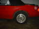 1991 Ford Crown Victoria - A red convertible is parked indoors, with a focus on its side profile and wheel.