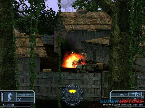 Military jeep engulfed in flames next to a wooden fence and buildings