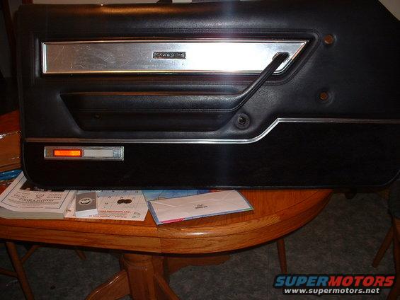 Black car door panel with chrome trim and a silver insert that reads "COUGAR"