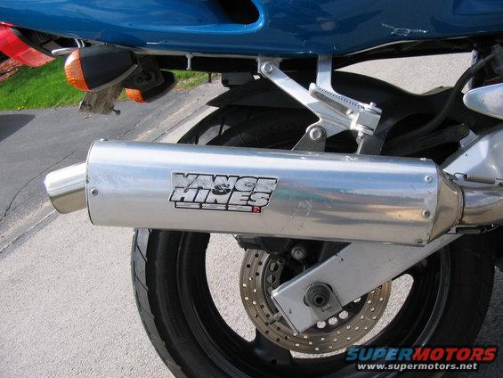 Motorcycle exhaust pipe with Vance & Hines logo, rear tire, and brake disc visible