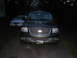 1997 Ford Expedition - Frontal view of a dark green SUV, a prominent chrome grille and headlights. Another vehicle is visible in the background.