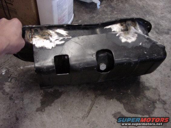 hand holding a black metal oil pan with some rust spots