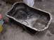 1998 Volkswagen Jetta - An oil pan sits on a concrete floor, showing signs of wear and tear.