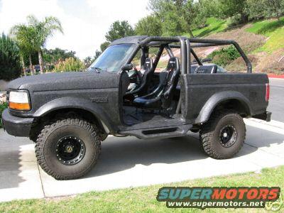 Black Ford Bronco with roll cage and racing seats, off-road tires, and aftermarket bumper