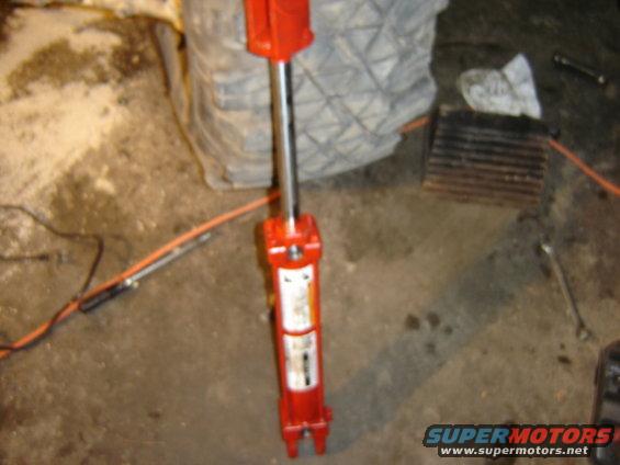 red hydraulic jack on concrete floor with orange cord