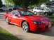 1999 Mitsubishi 3000GT - A red 1999 Mitsubishi 3000GT is parked on a driveway, with other vehicles in the background.