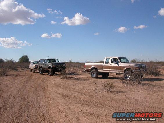 1992 Ford F-150 and a Bronco driving on a dirt road