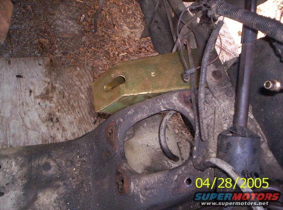 Close-up of a vehicle's suspension component with a brass-colored bracket attached