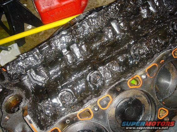 Engine block covered in thick, black sludge with orange gasket material visible