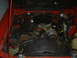1986 Ford Mustang - The engine bay of a red 1986 Ford Mustang shows a V8 engine with various components and wiring.