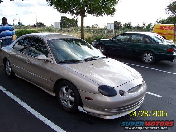 1998 Mercury Sable sedan parked in a lot next to a dark green sedan
