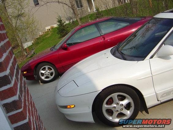 Two red and white Ford Probes parked side-by-side, front view