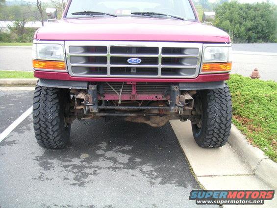 Red Ford Bronco front view, lifted with large tires, missing bumper