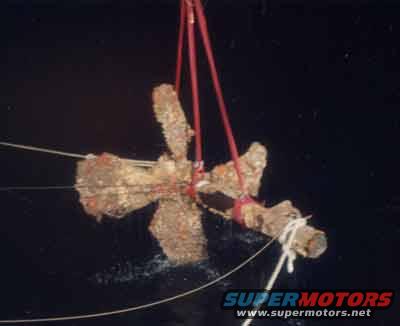 Boat propeller being lifted out of the water by red straps and ropes