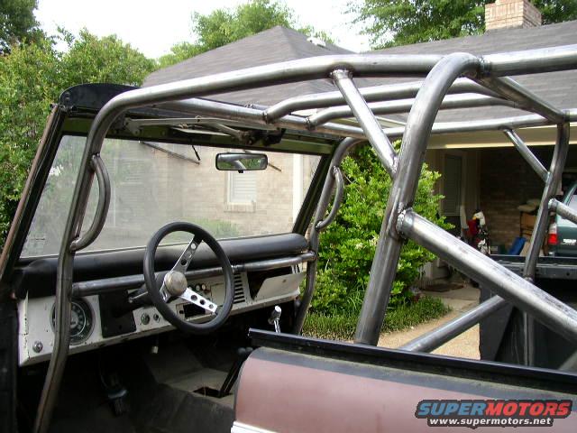 Interior of a Ford Bronco with a custom roll cage, showing the dashboard and steering wheel
