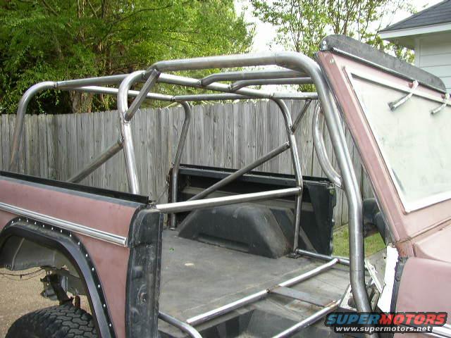 Brown Ford Bronco with a custom silver roll cage, viewed from the rear