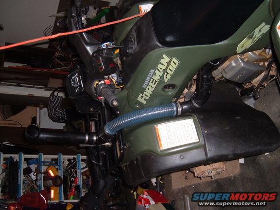 Green Honda Foreman 500 ATV side view with blue hose
