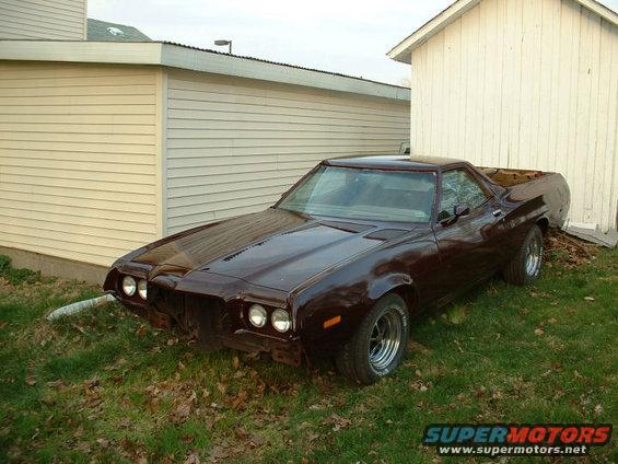 Dark red 1972 Ford Ranchero parked on grass next to a building